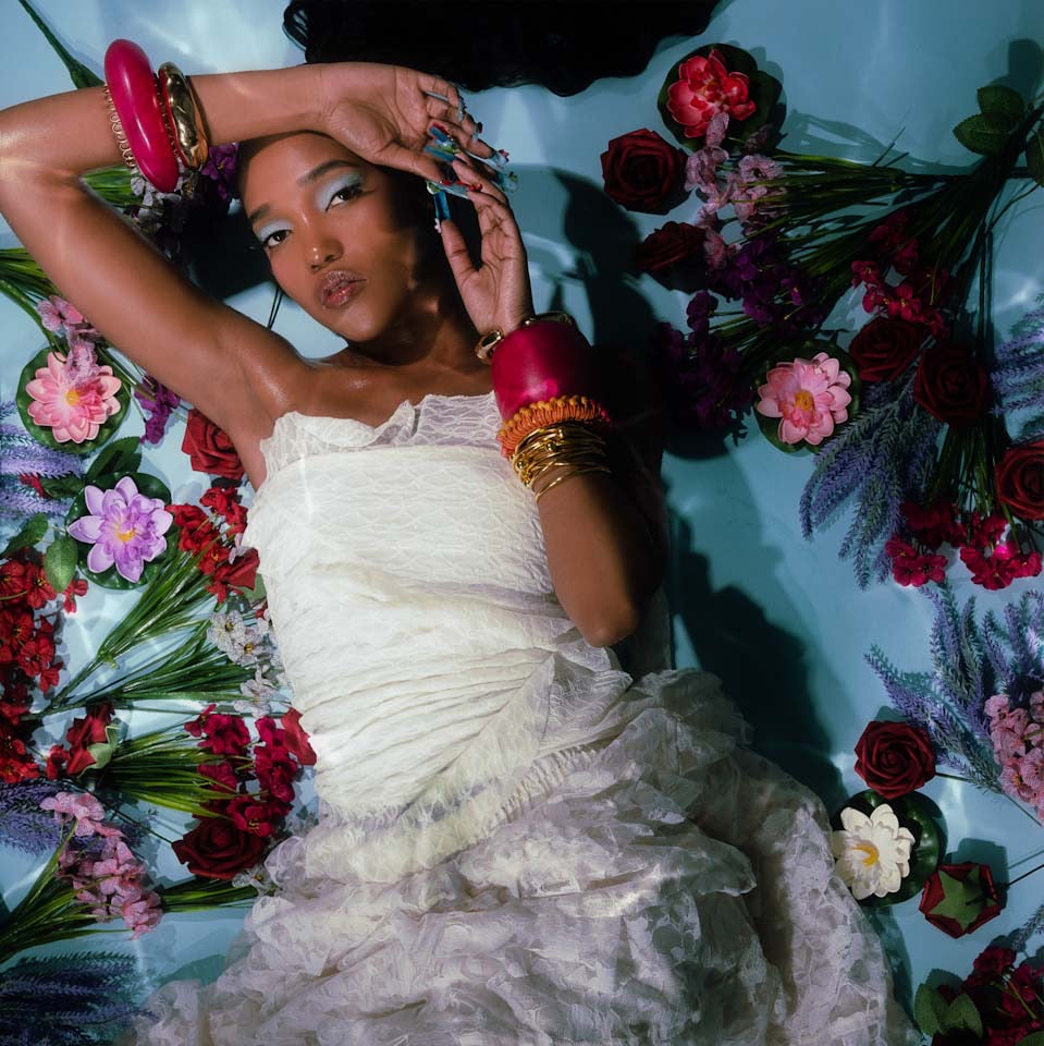 person in a white dress surrounded by flowers on a blue background